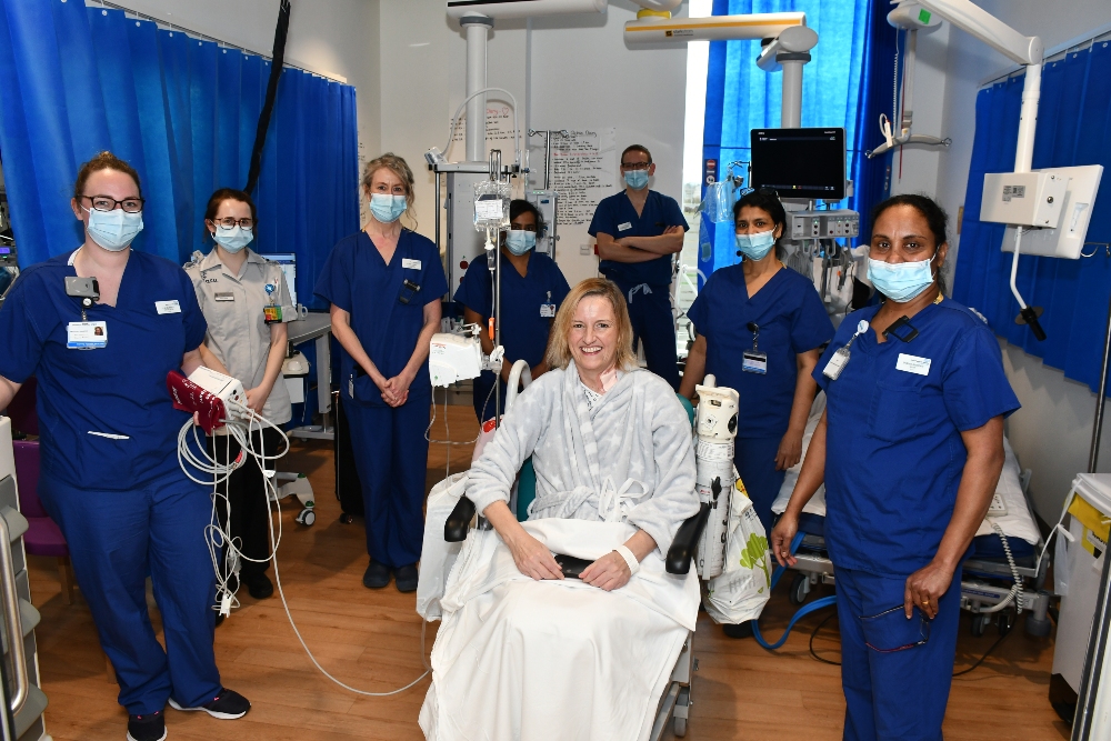 A woman in a wheelchair surrounding by medical staff.