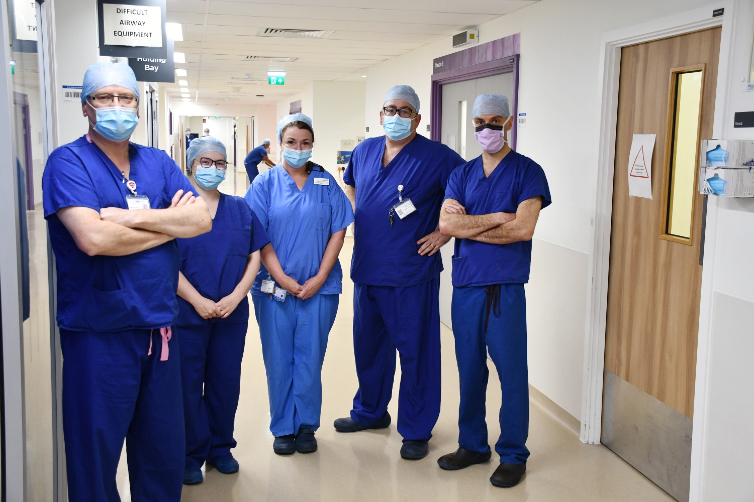 Five people wearing blue scrubs standing inside.