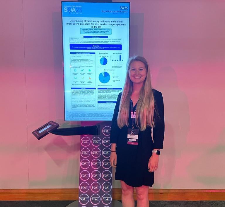 A blonde haired woman standing in front of a vertical digital screen