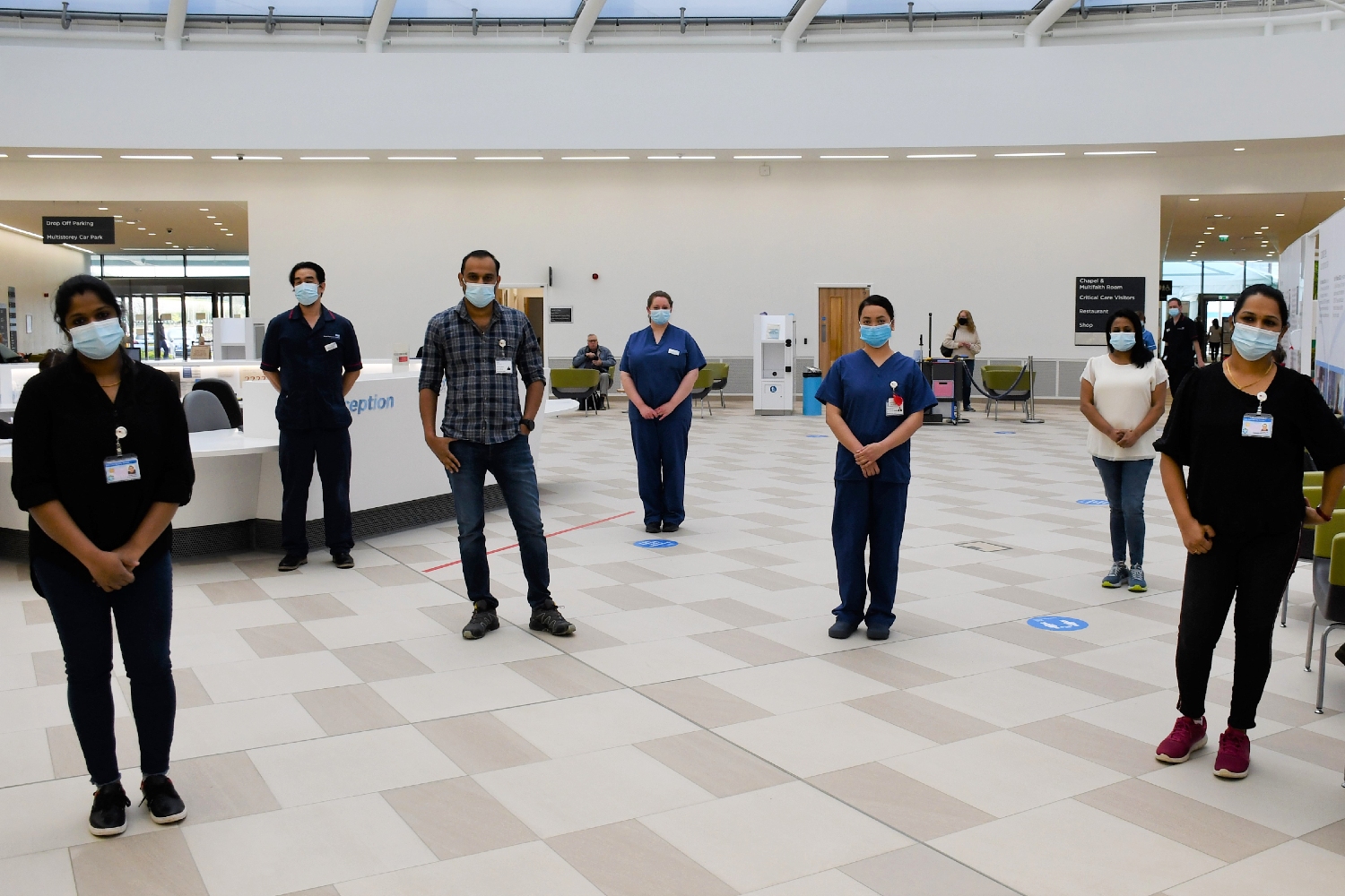 Seven people stand on a white and grey checkerboard floor 