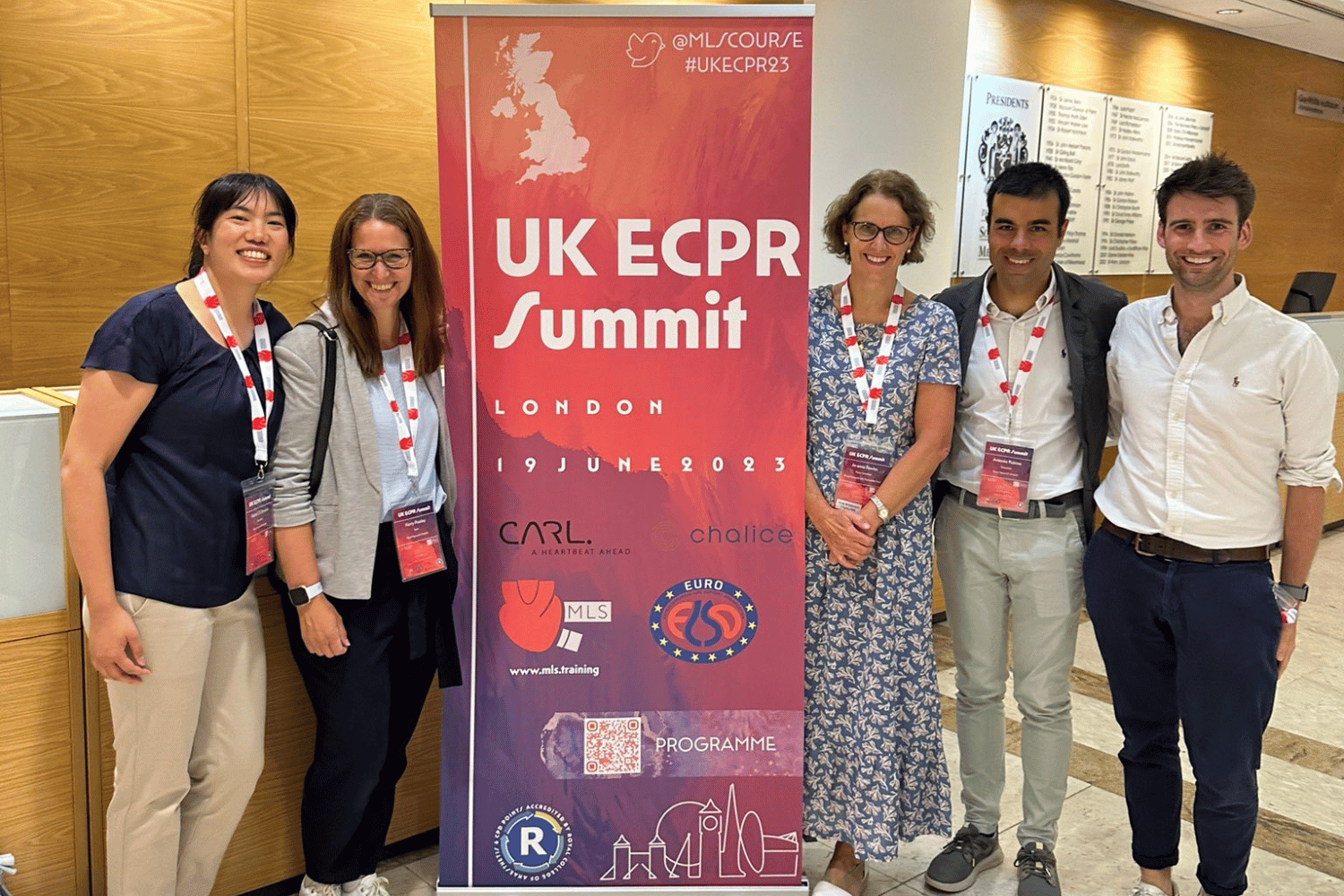 Five people standing either side of a pull-up banner which says UK ECPR summit - London June 2023