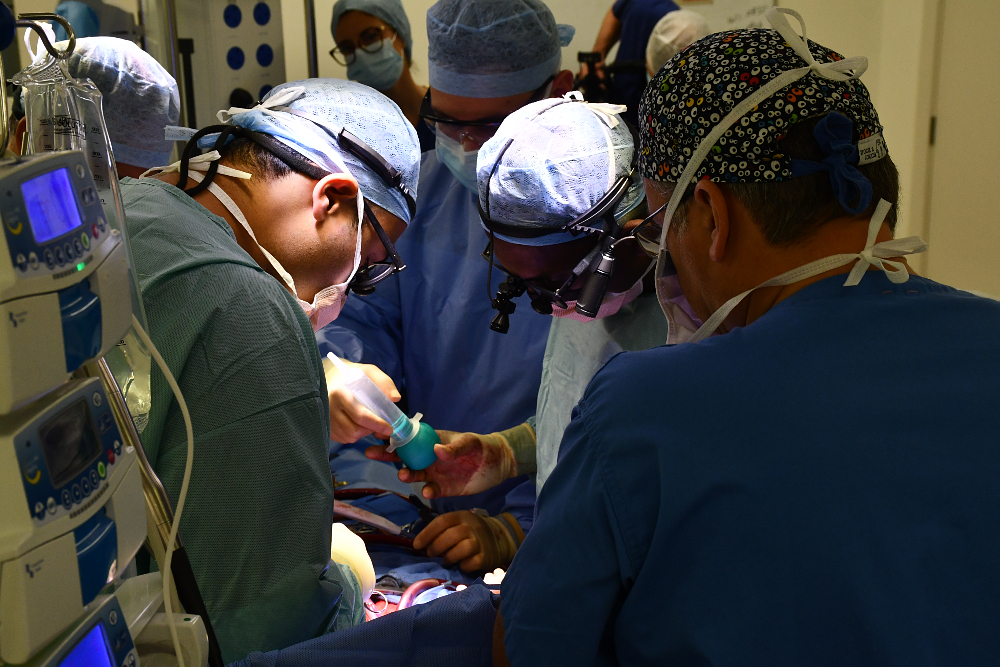 People in blue gowns and hats operating.