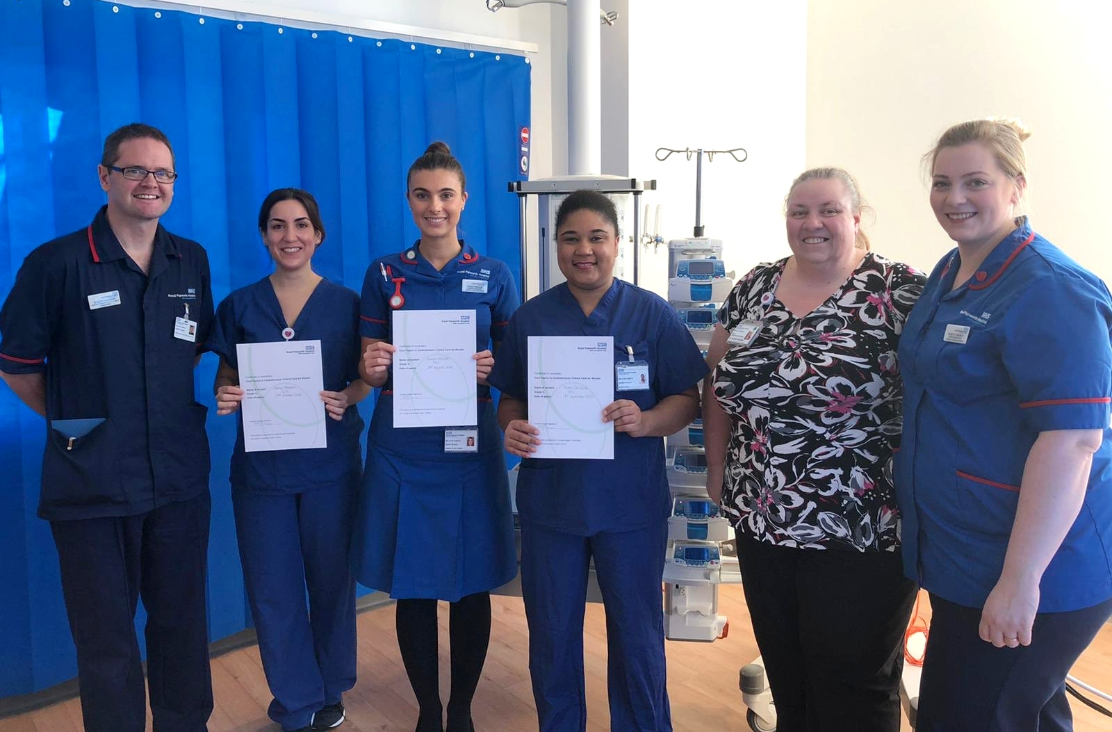 Six people standing inside, with three of holding certificates in front of them. 