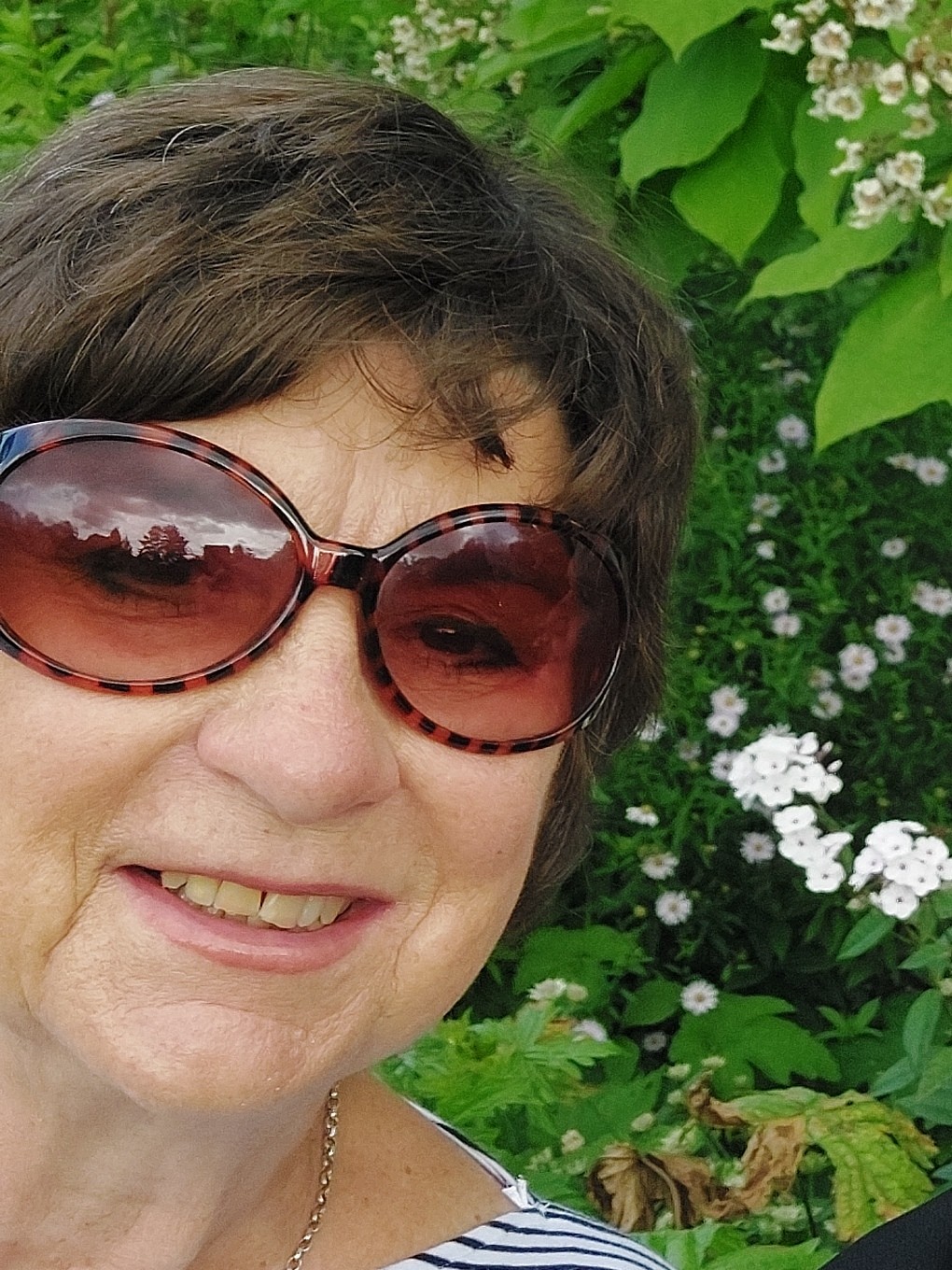 Lady outside wearing sunglasses and smiling 