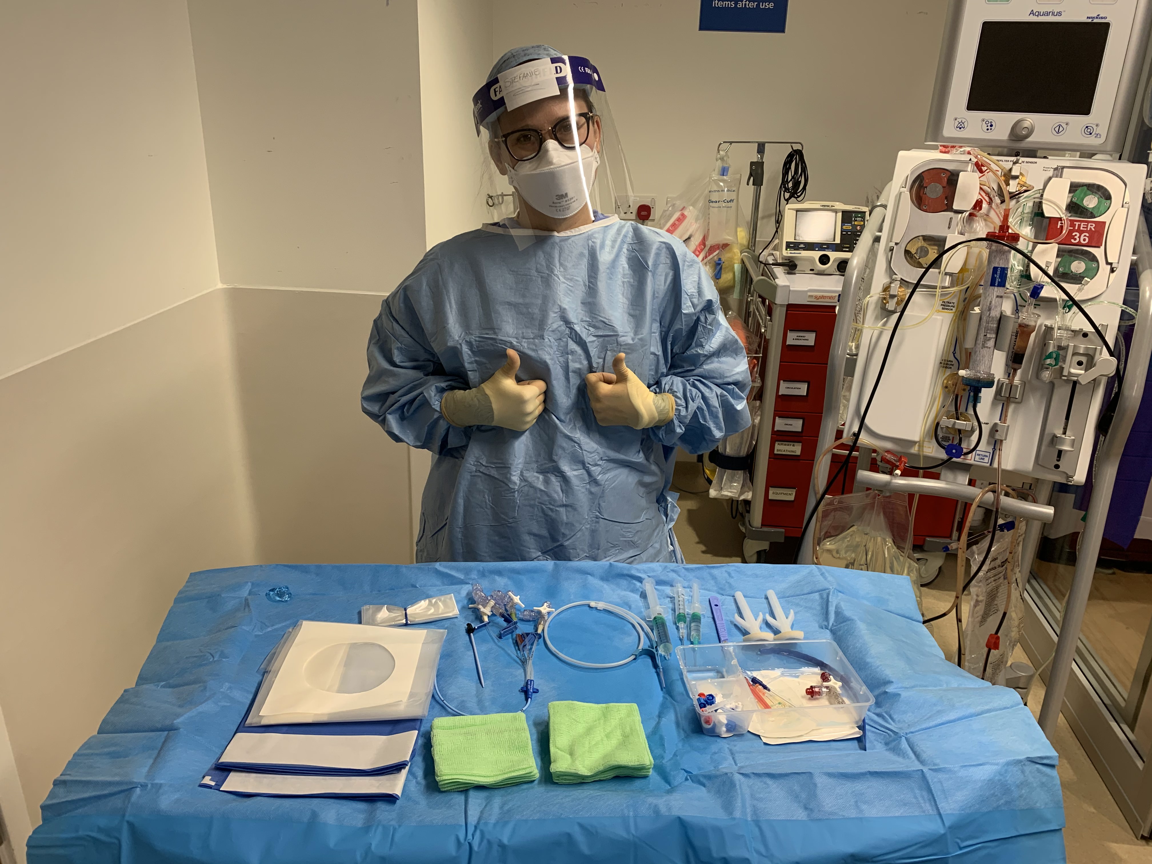 A person in protective equipment with instruments on a table.