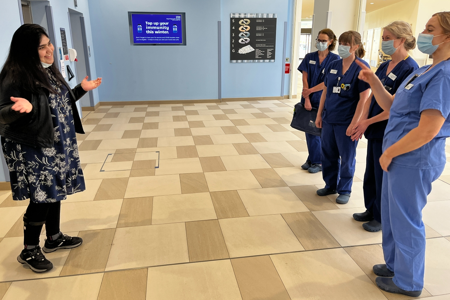 Areeb talking to four nurses in blue scrubs